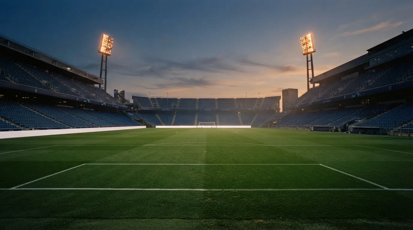 An empty football stadium with floodlight masts at dusk