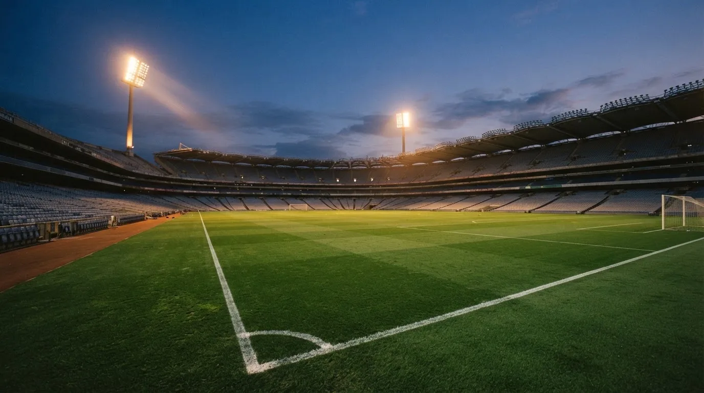An empty football stadium with floodlight masts at dusk