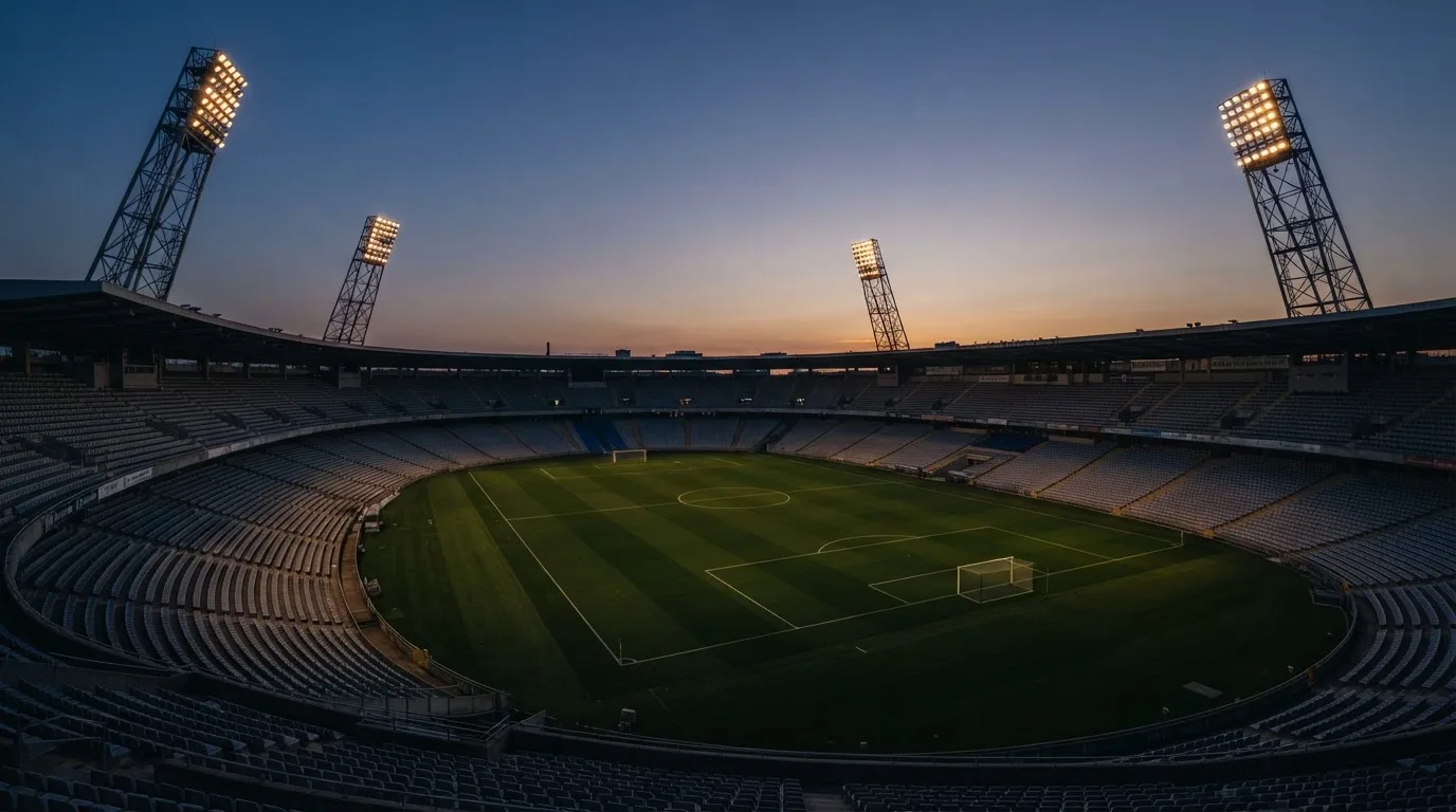 An empty football stadium with floodlight masts at dusk
