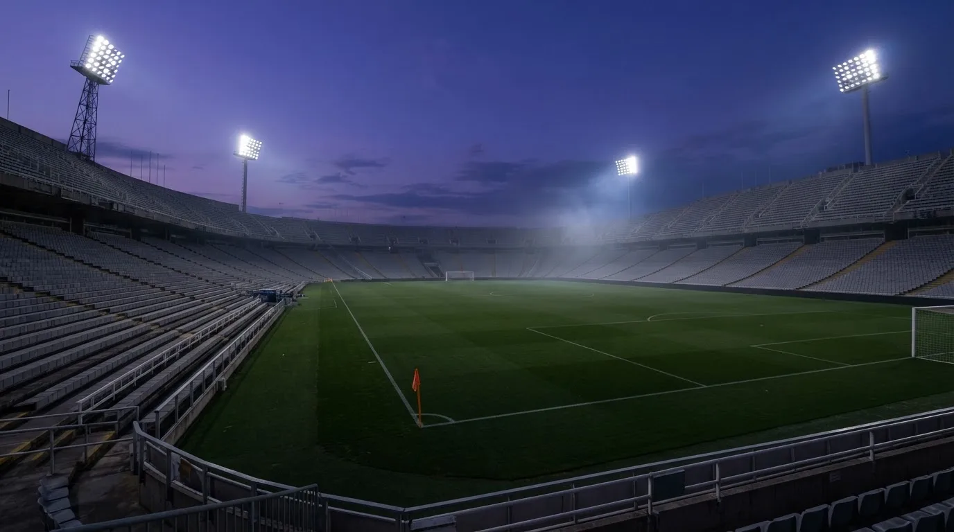 An empty football stadium with floodlight masts at dusk