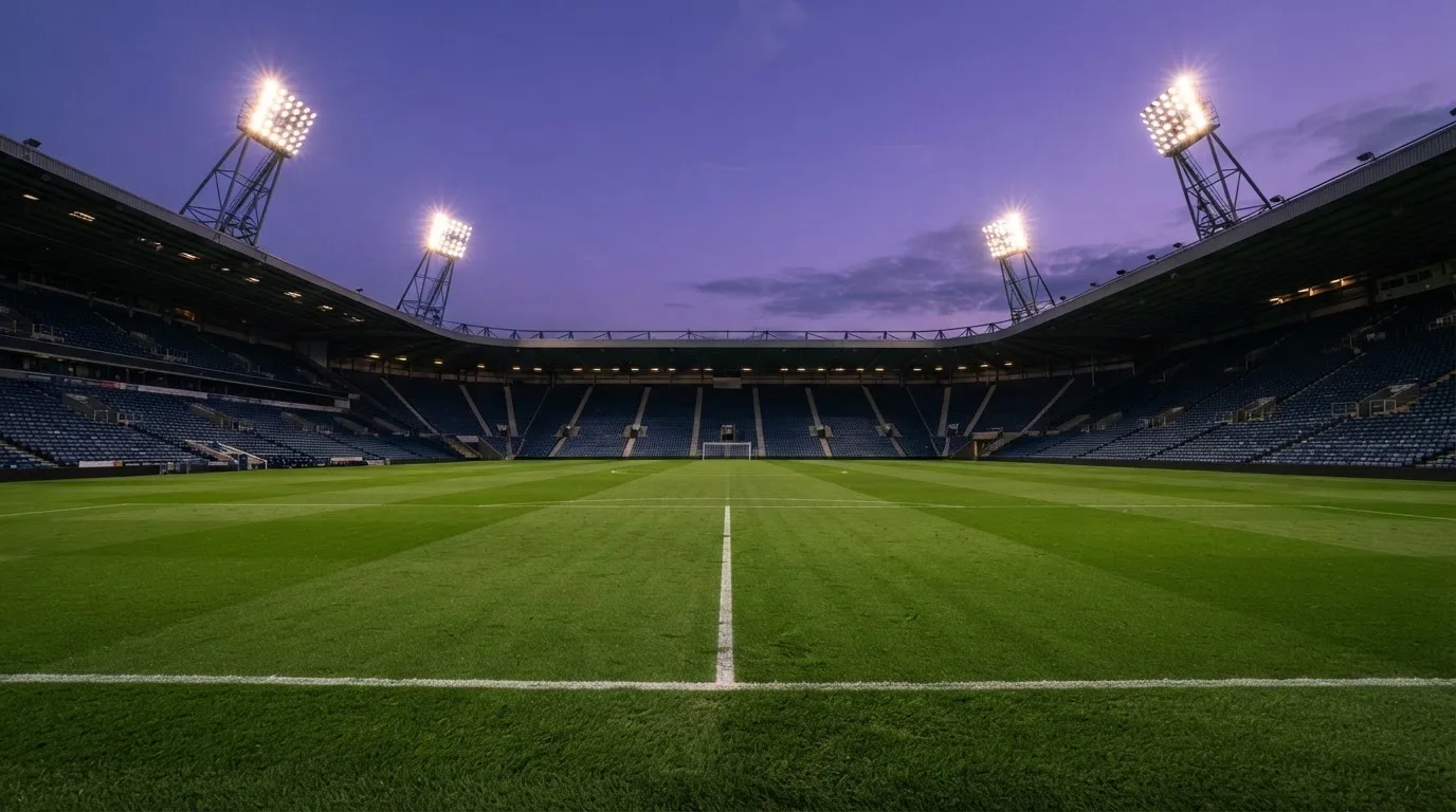 An empty football stadium with floodlight masts at dusk