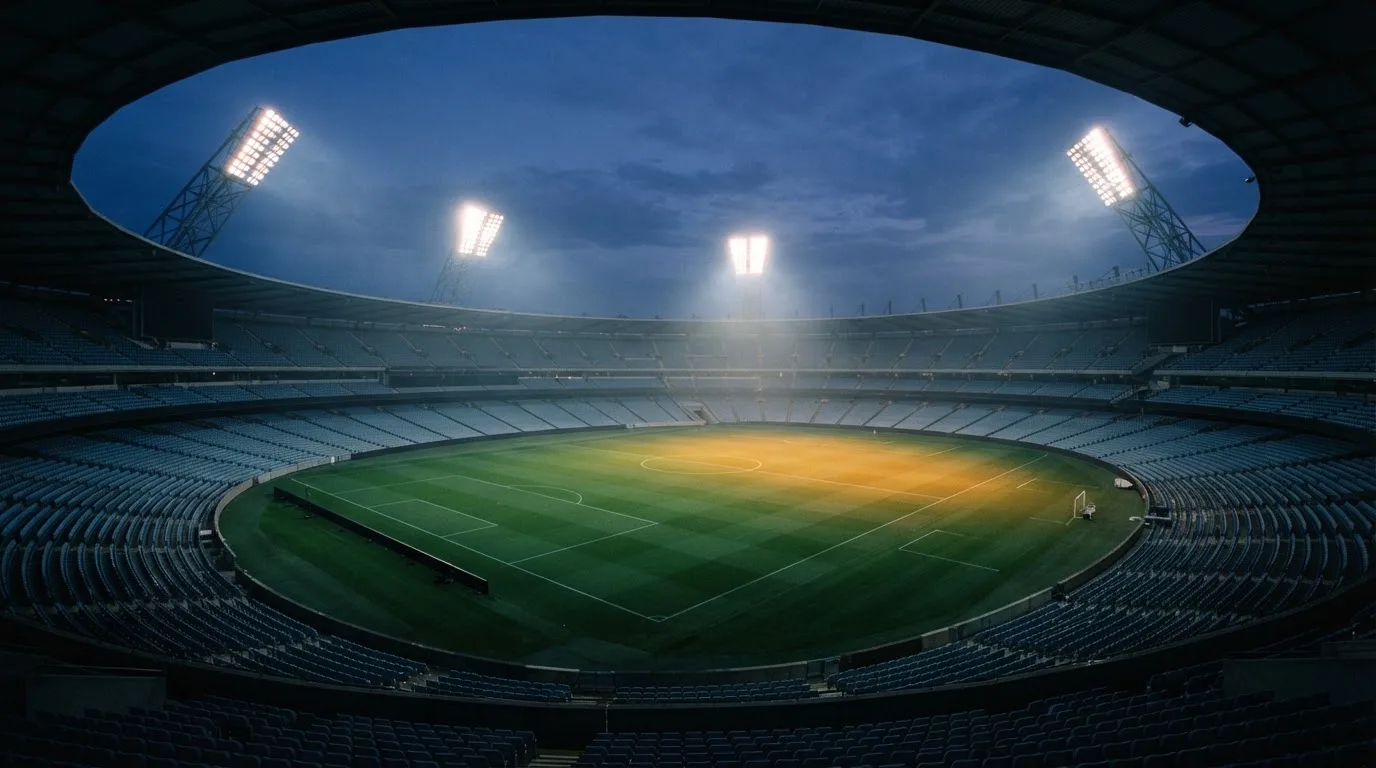 An empty football stadium with floodlight masts at dusk
