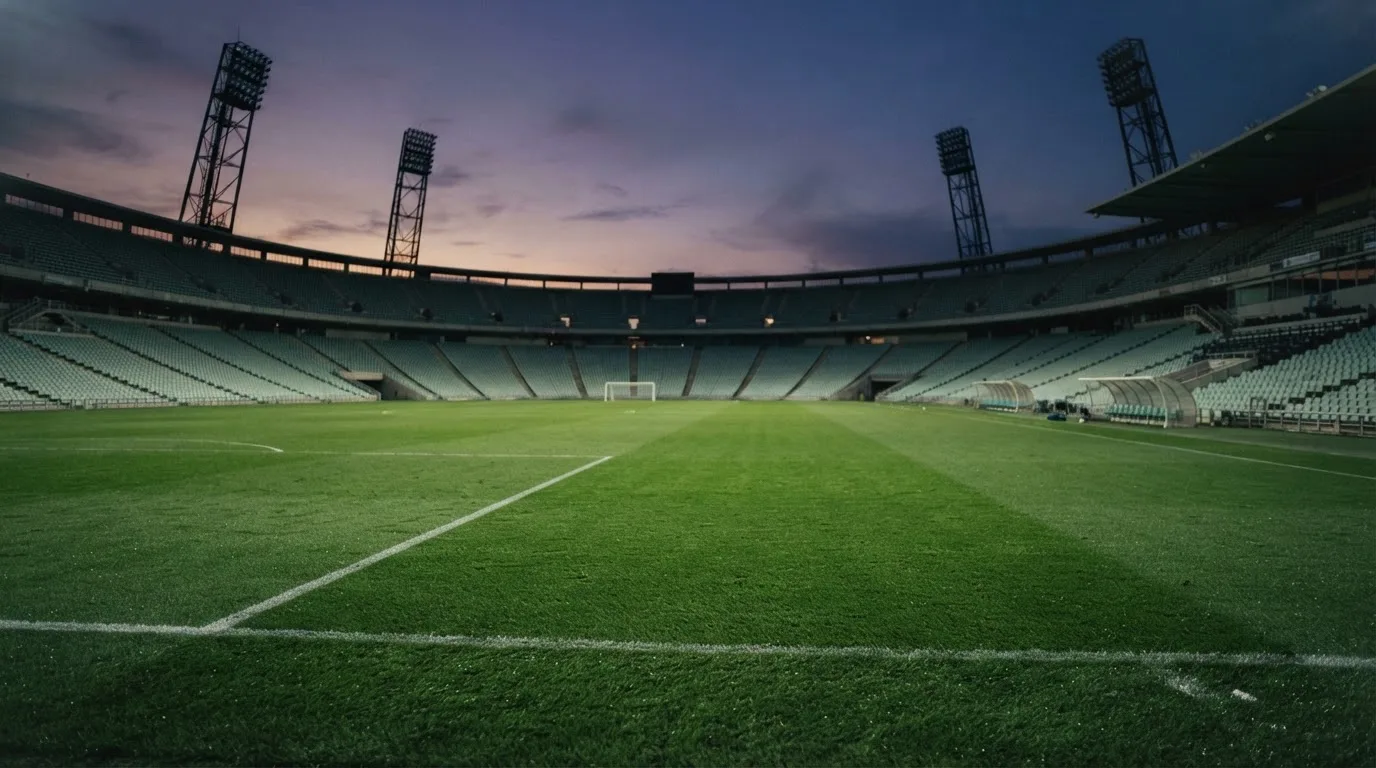 An empty football stadium with floodlight masts at dusk