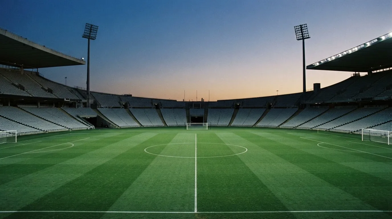 An empty football stadium with floodlight masts at dusk