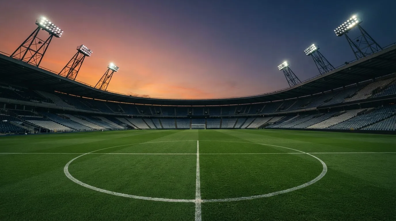 An empty football stadium with floodlight masts at dusk
