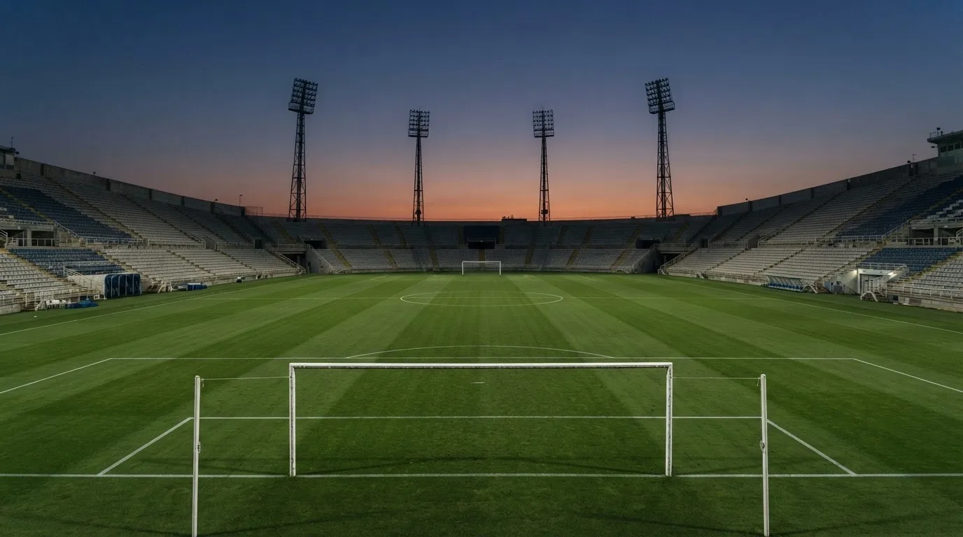 An empty football stadium with floodlight masts at dusk