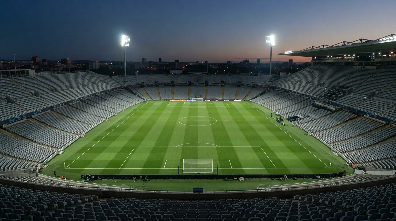 An empty football stadium with floodlight masts at dusk
