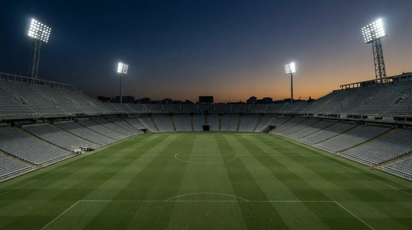 An empty football stadium with floodlight masts at dusk