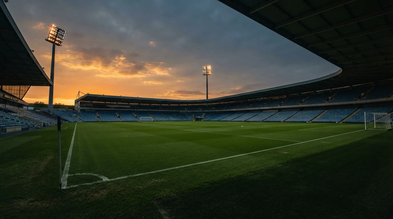 An empty football stadium with floodlight masts at dusk