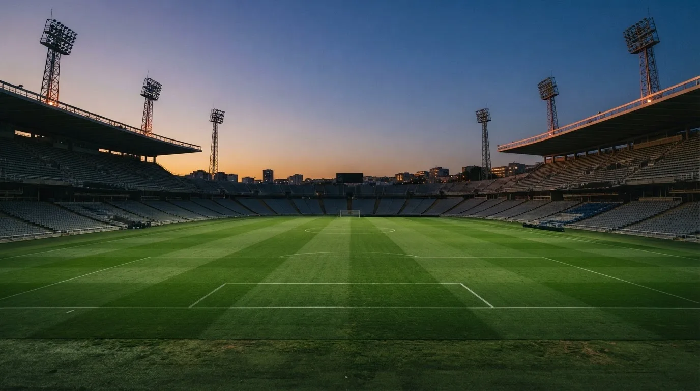 An empty football stadium with floodlight masts at dusk