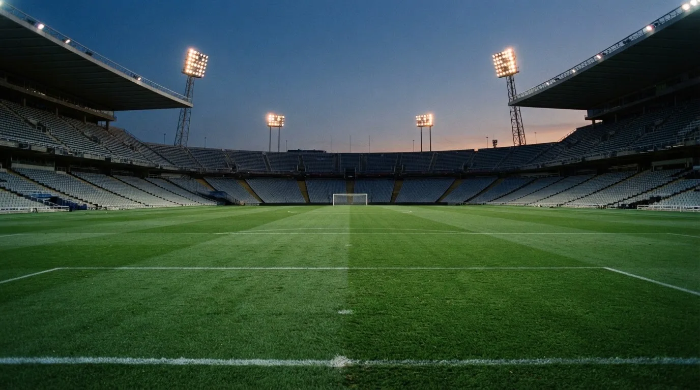 An empty football stadium with floodlight masts at dusk