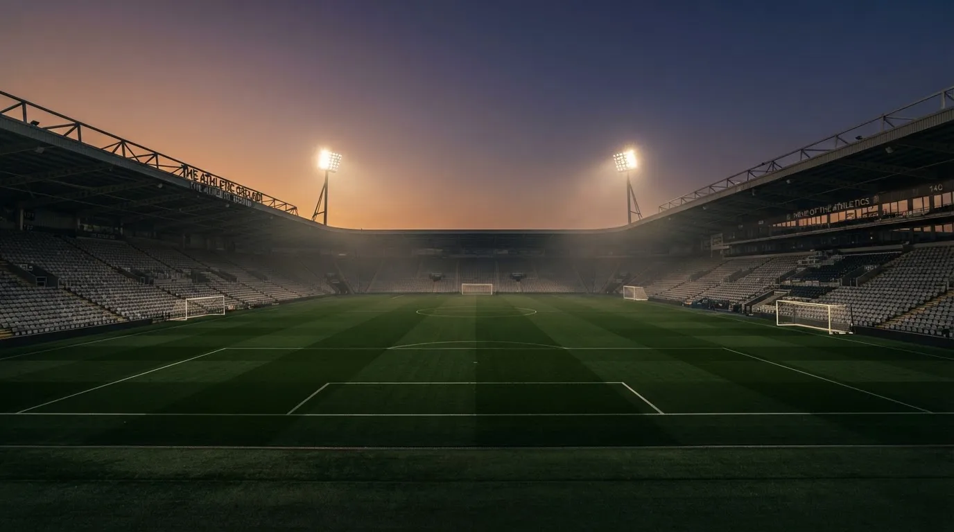 An empty football stadium with floodlight masts at dusk