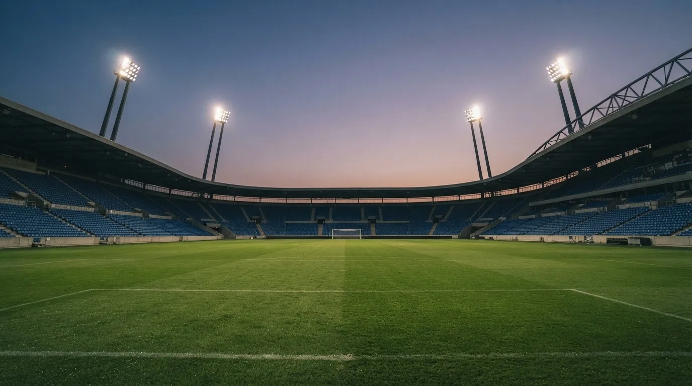 An empty football stadium with floodlight masts at dusk
