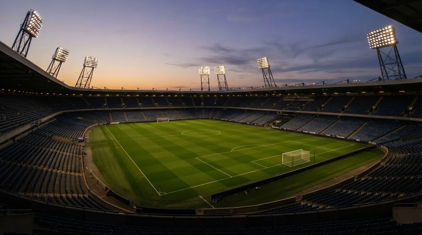An empty football stadium with floodlight masts at dusk