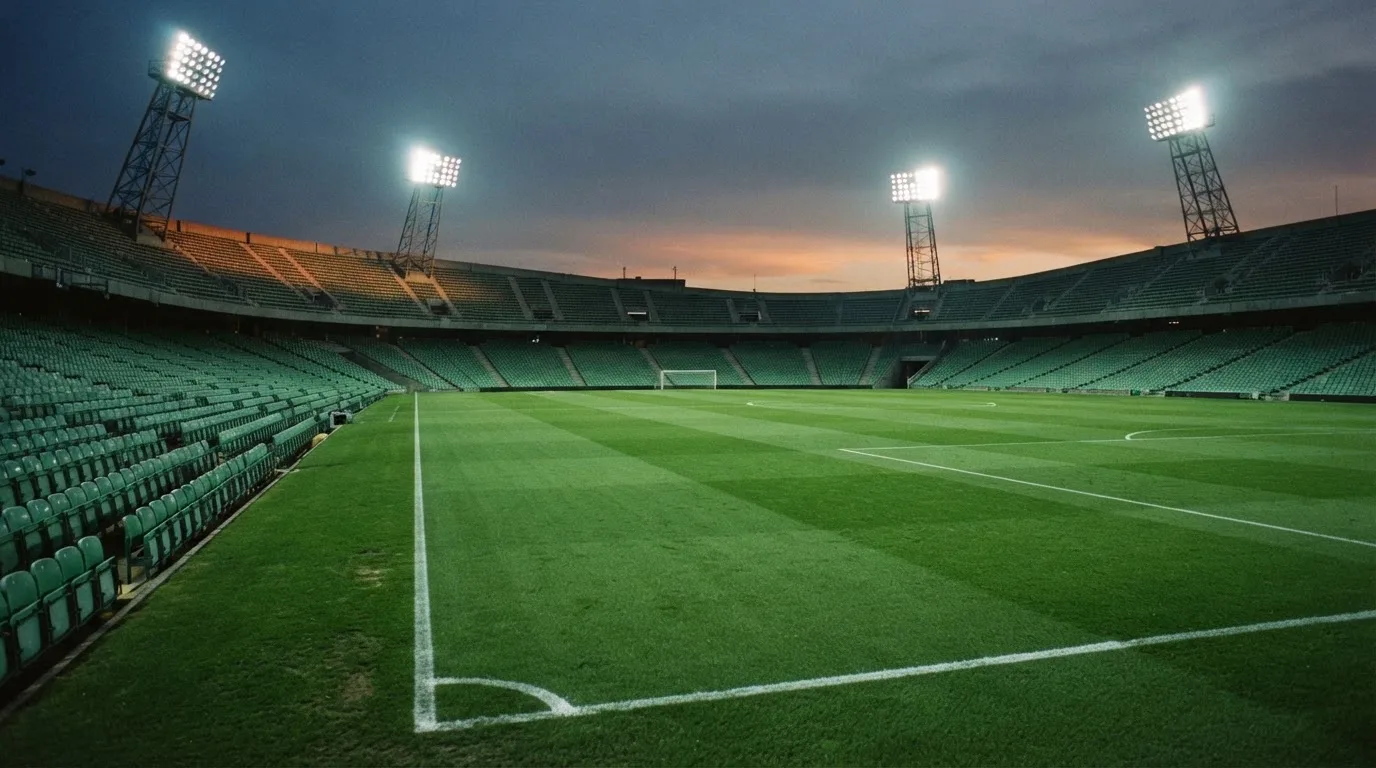 An empty football stadium with floodlight masts at dusk