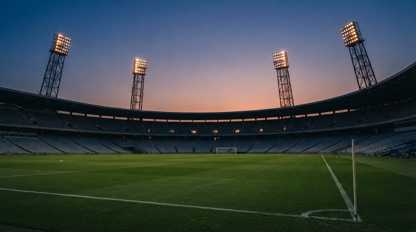 An empty football stadium with floodlight masts at dusk