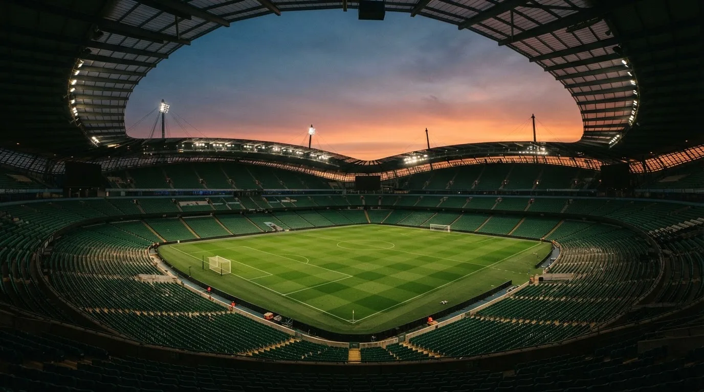 An empty football stadium with floodlight masts at dusk