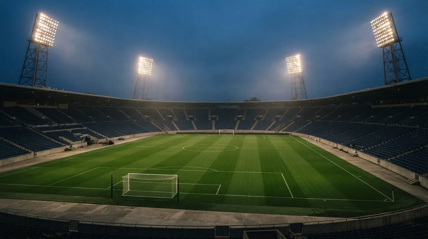 An empty football stadium with floodlight masts at dusk