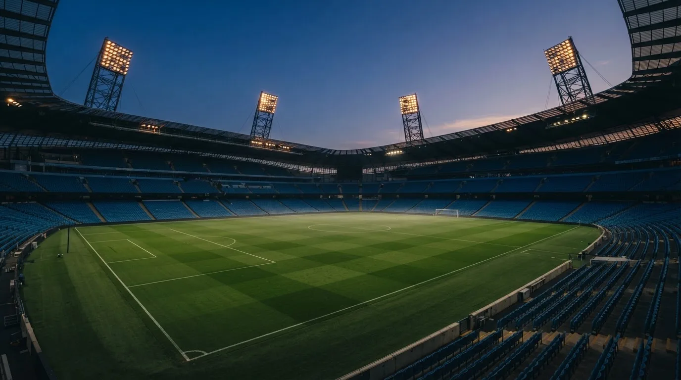 An empty football stadium with floodlight masts at dusk