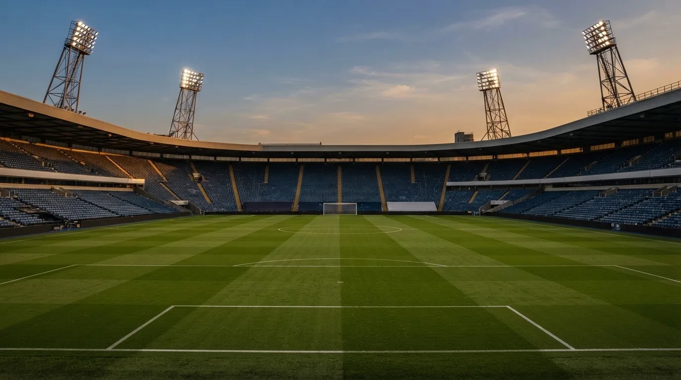 An empty football stadium with floodlight masts at dusk