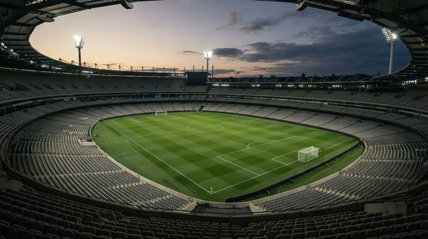 An empty football stadium with floodlight masts at dusk
