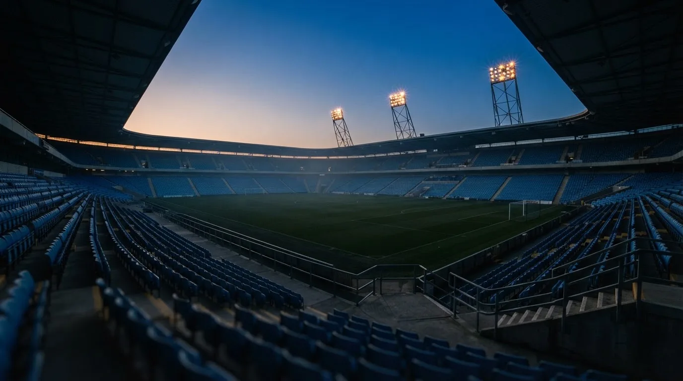 An empty football stadium with floodlight masts at dusk