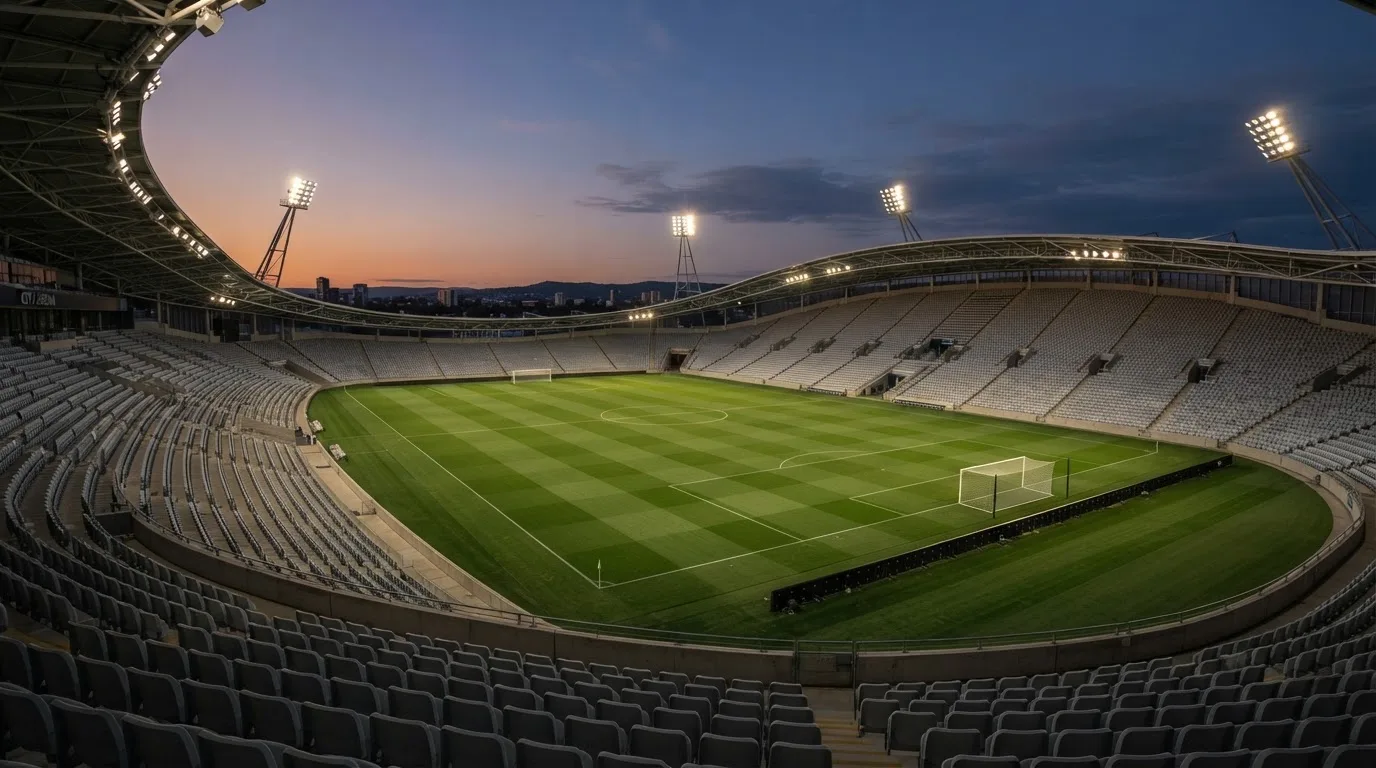 An empty football stadium with floodlight masts at dusk