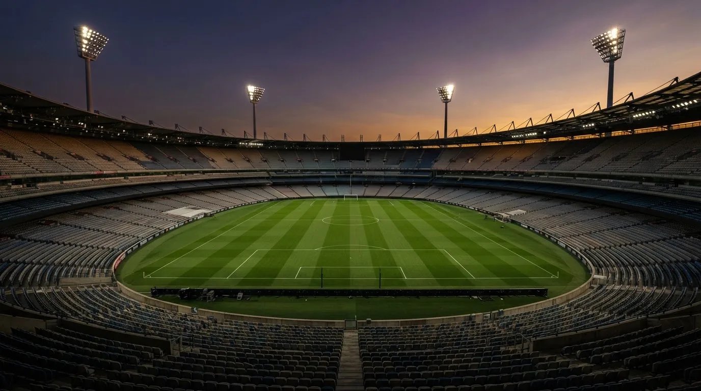 An empty football stadium with floodlight masts at dusk