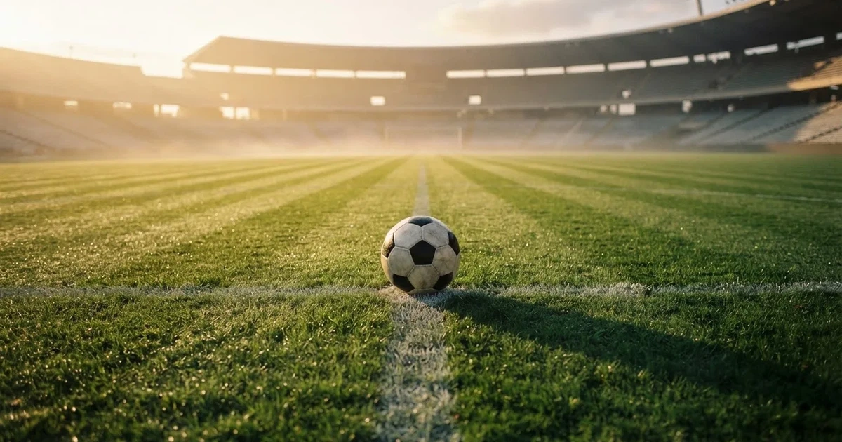 A ball on the centre spot of a grass pitch in morning light