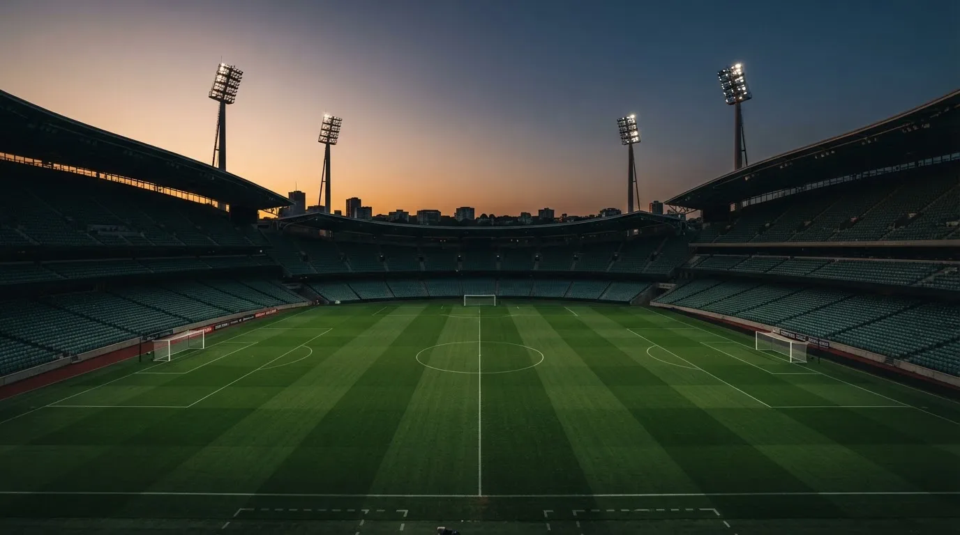 An empty football stadium with floodlight masts at dusk