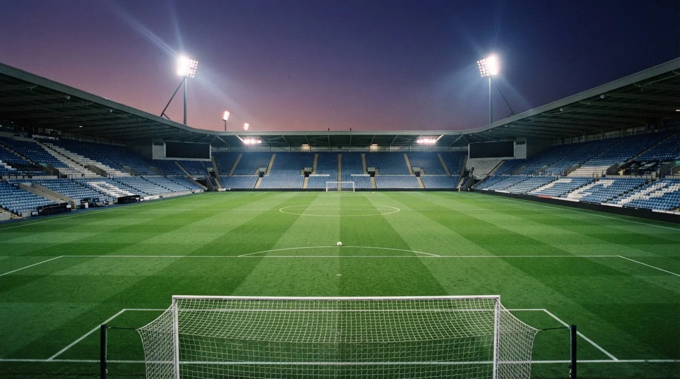 An empty football stadium with floodlight masts at dusk