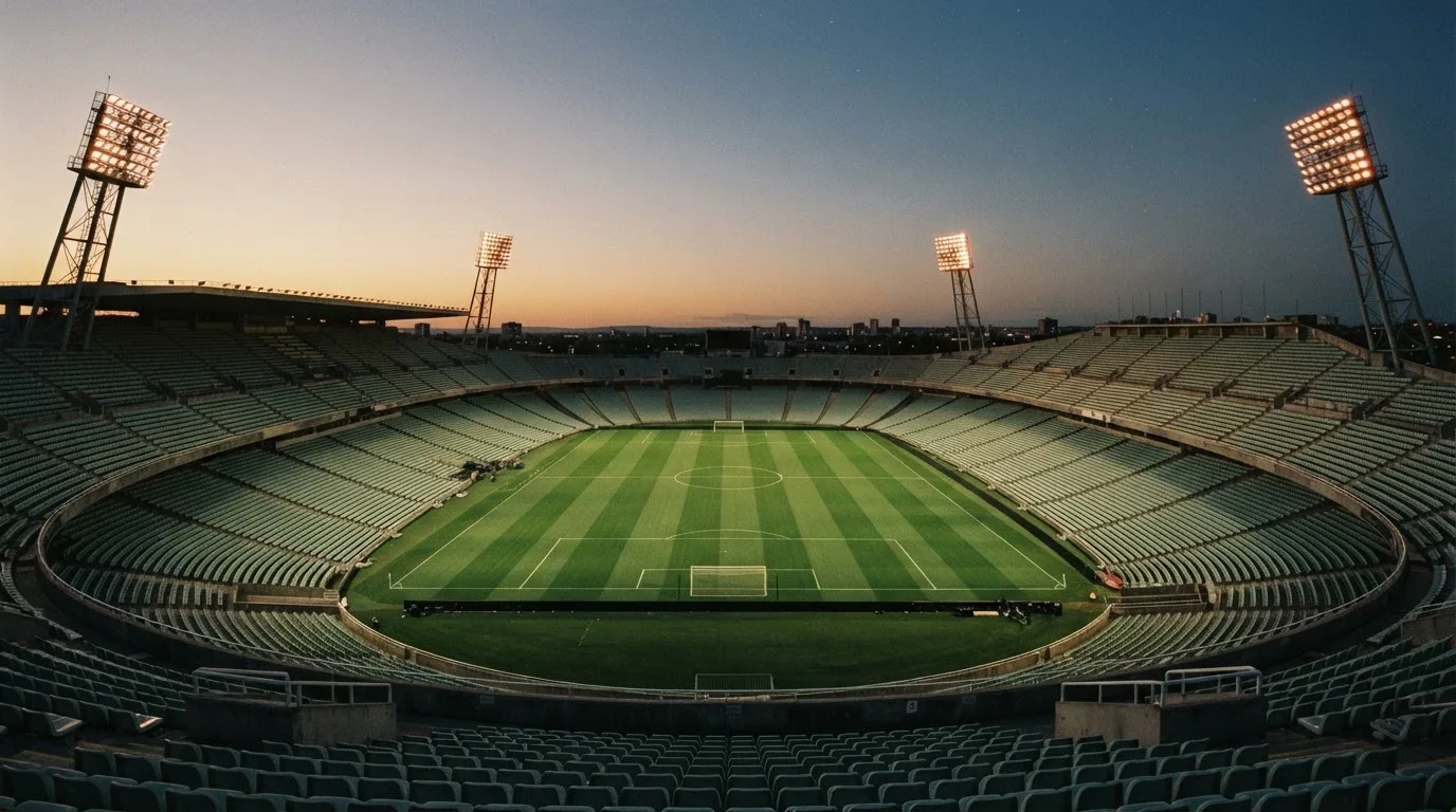 An empty football stadium with floodlight masts at dusk