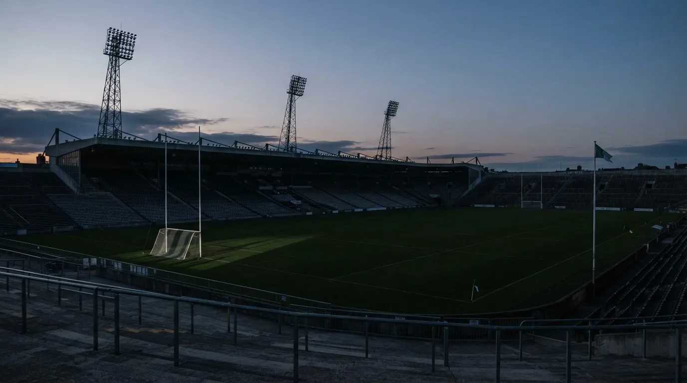 An empty football stadium with floodlight masts at dusk