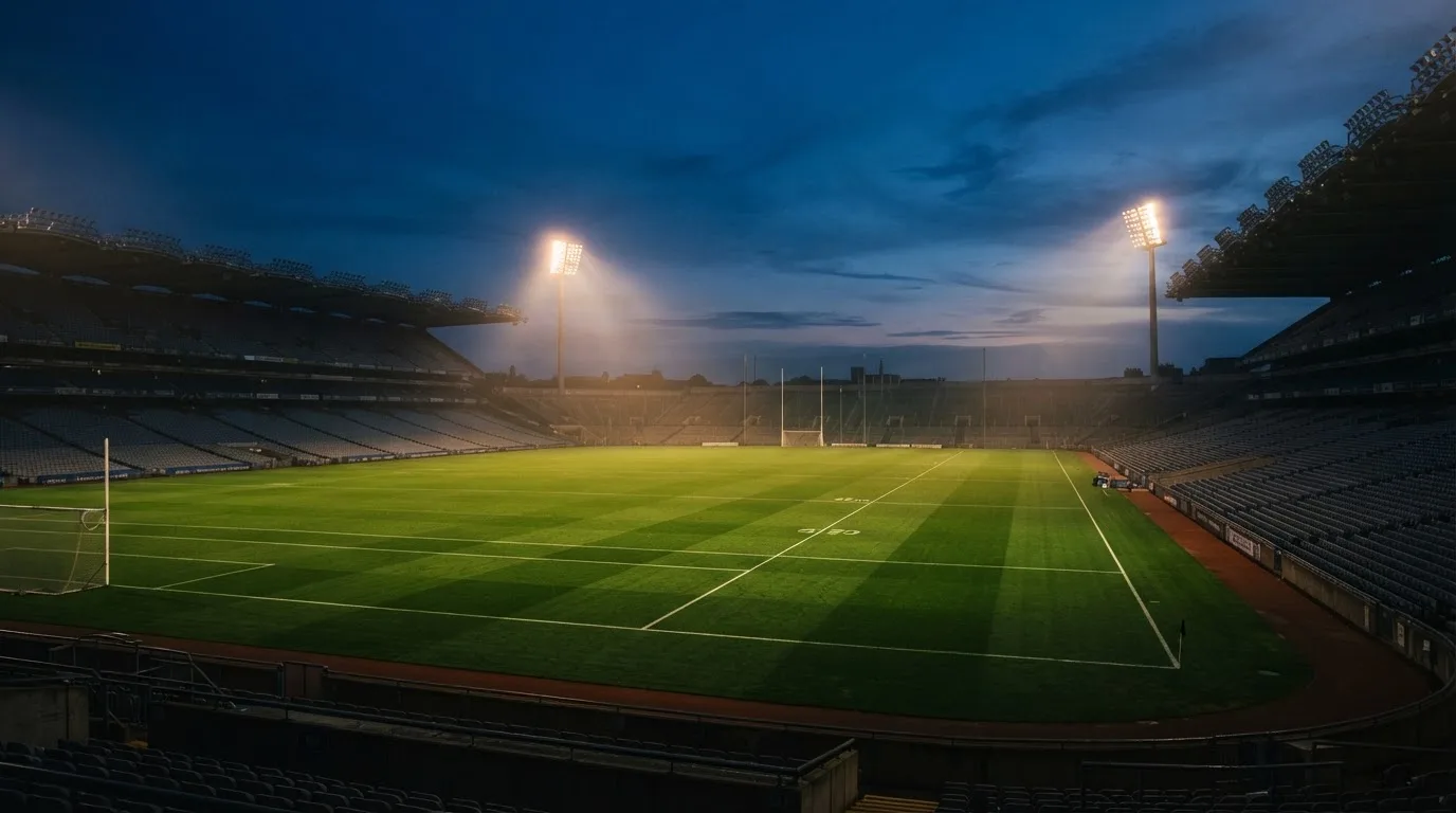An empty football stadium with floodlight masts at dusk