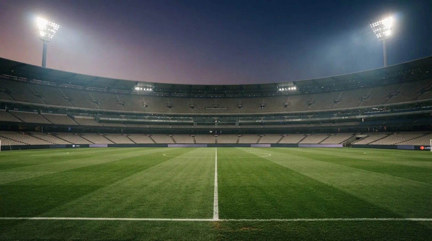 An empty football stadium with floodlight masts at dusk