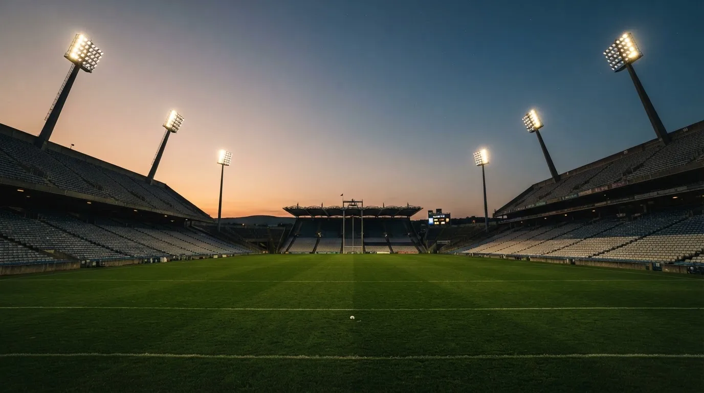 An empty football stadium with floodlight masts at dusk