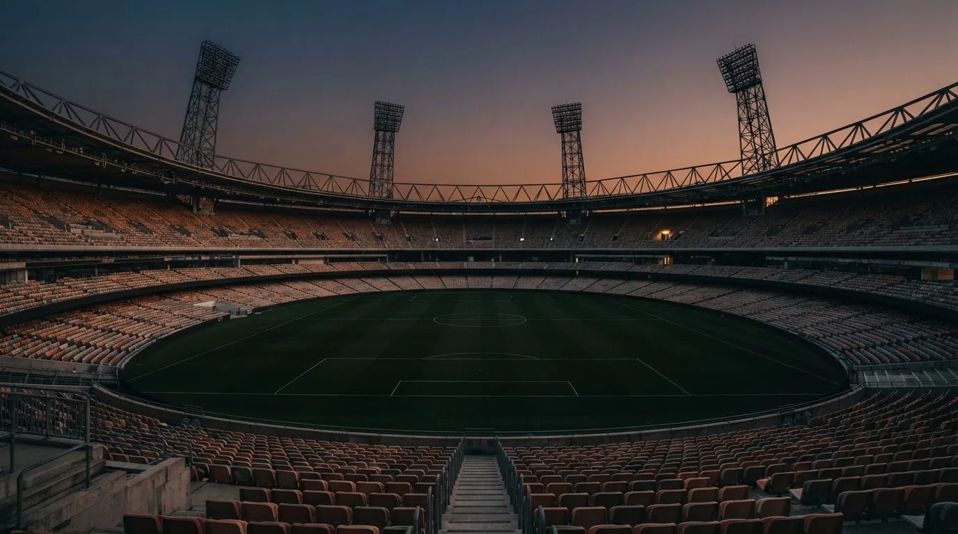An empty football stadium with floodlight masts at dusk