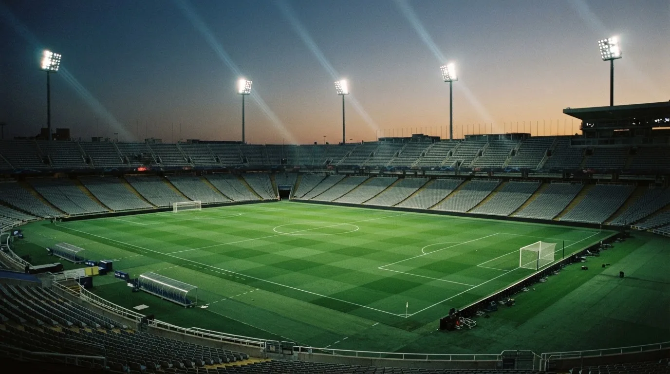 An empty football stadium with floodlight masts at dusk