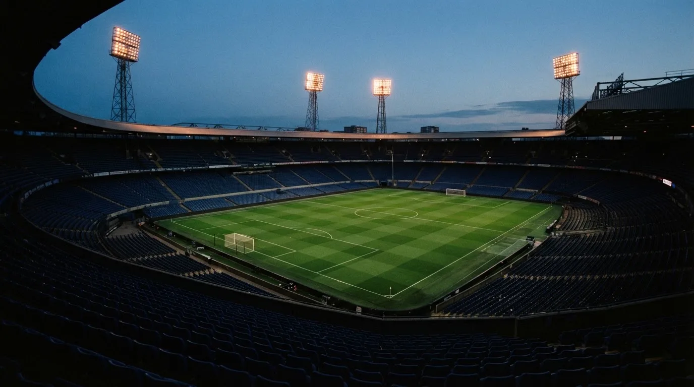 An empty football stadium with floodlight masts at dusk
