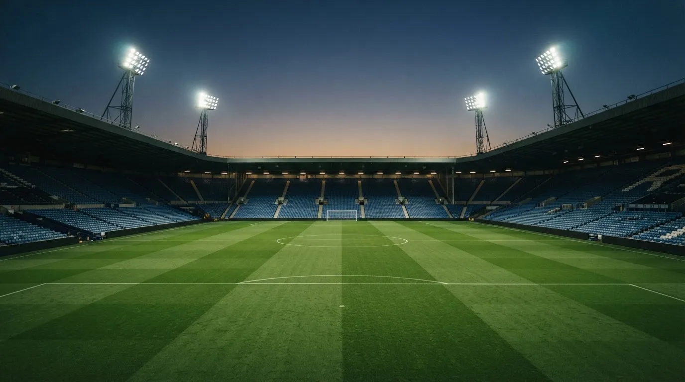 An empty football stadium with floodlight masts at dusk