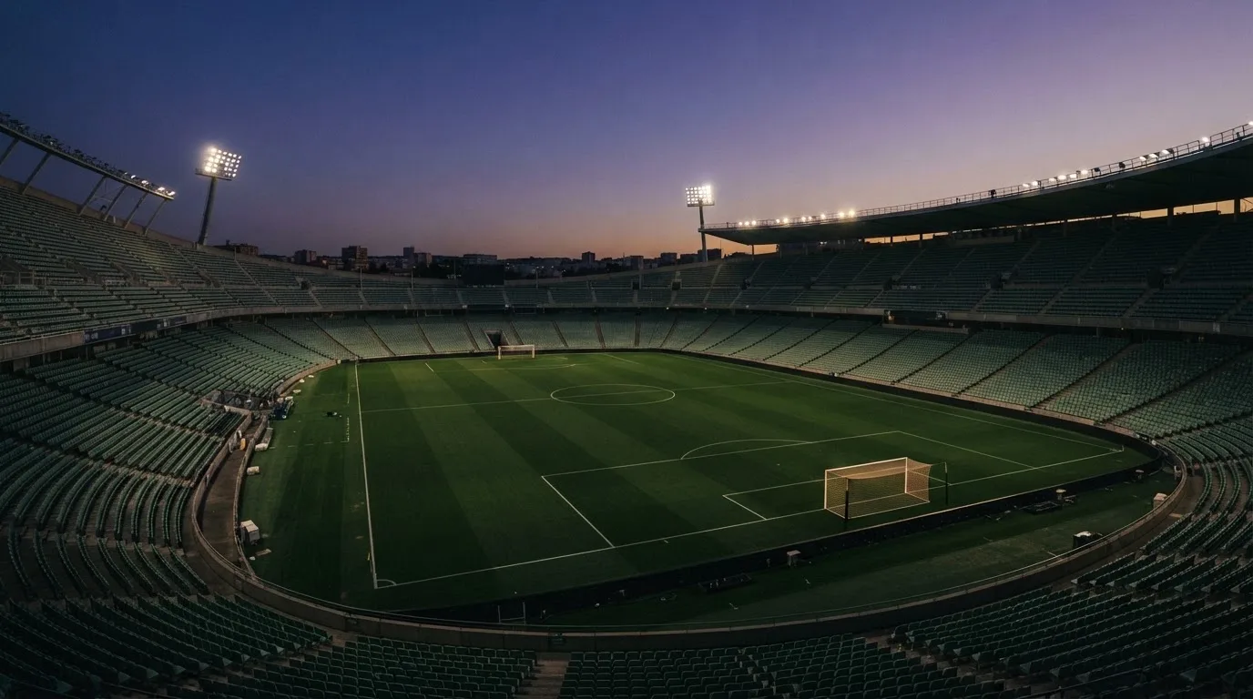 An empty football stadium with floodlight masts at dusk