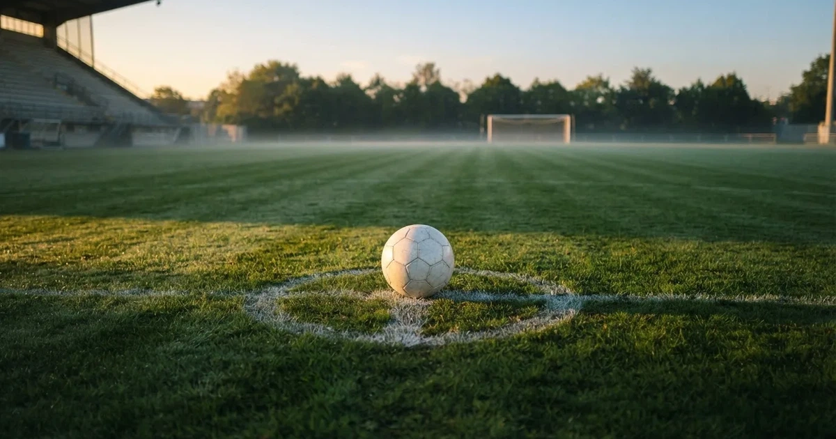 A ball on the centre spot of a grass pitch in morning light