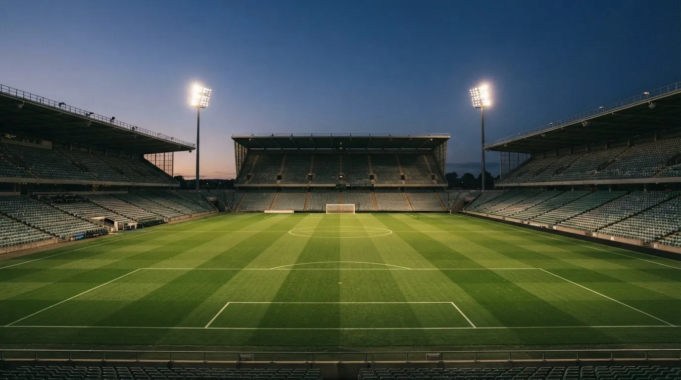 An empty football stadium with floodlight masts at dusk