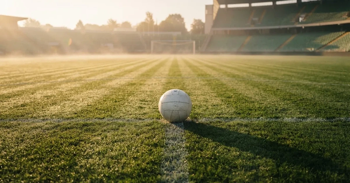 A ball on the centre spot of a grass pitch in morning light