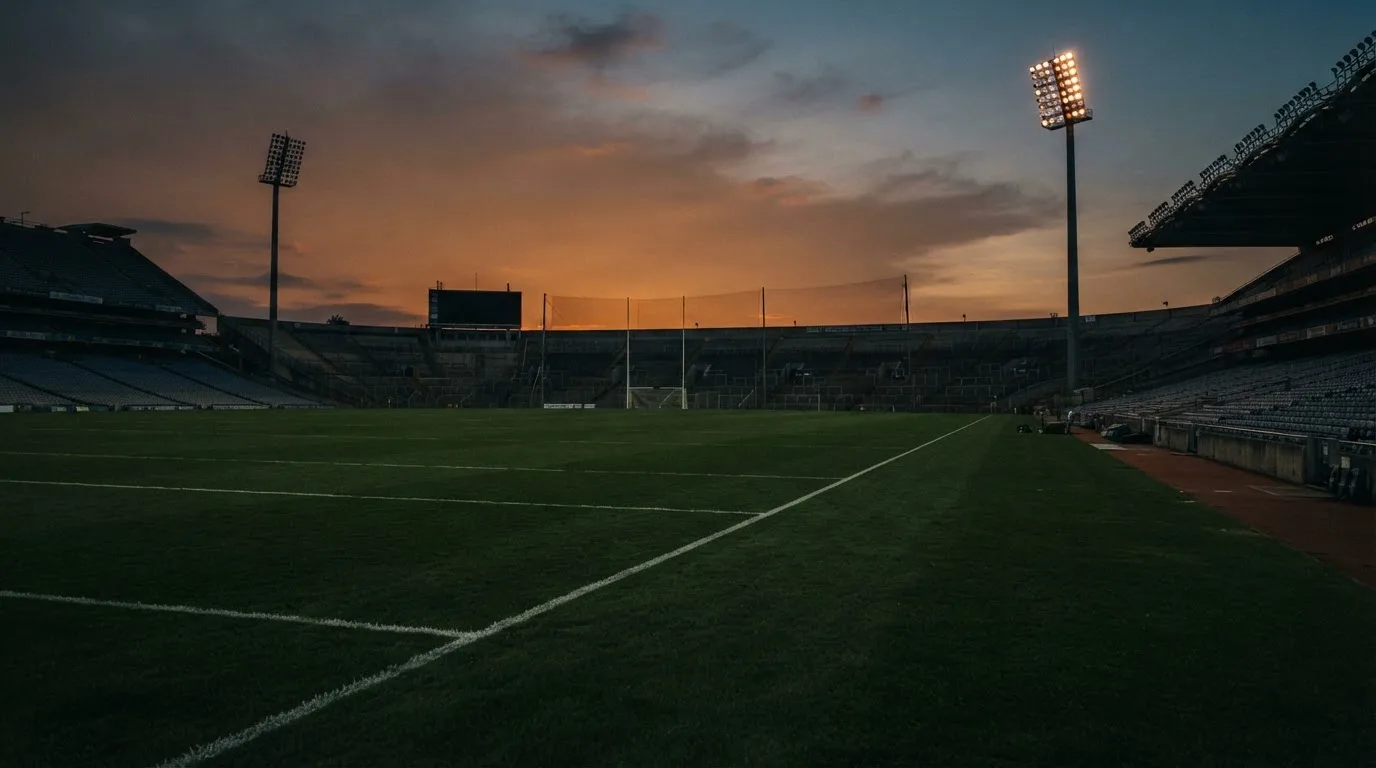 An empty football stadium with floodlight masts at dusk