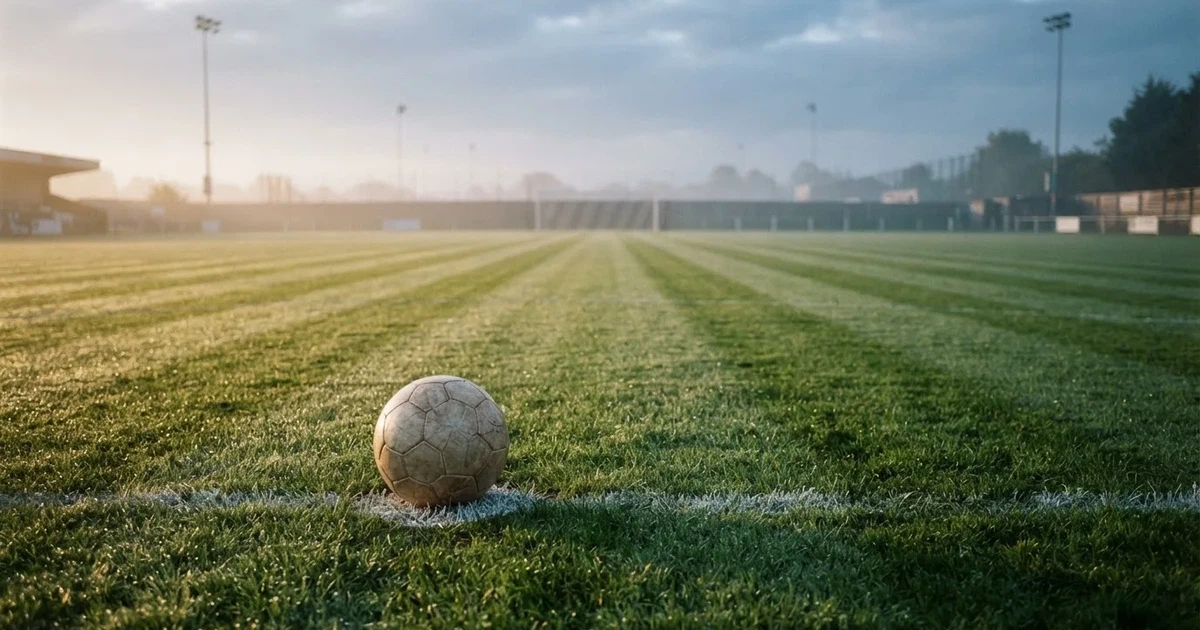A ball on the centre spot of a grass pitch in morning light