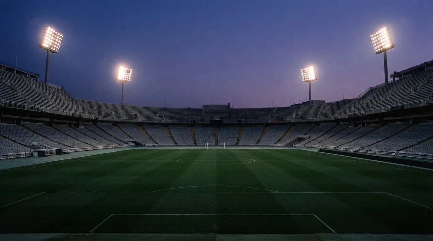 An empty football stadium with floodlight masts at dusk