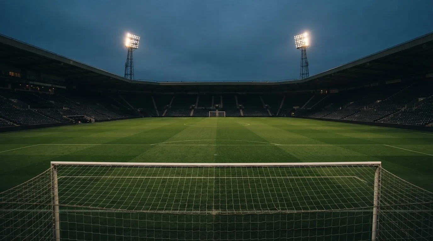 An empty football stadium with floodlight masts at dusk