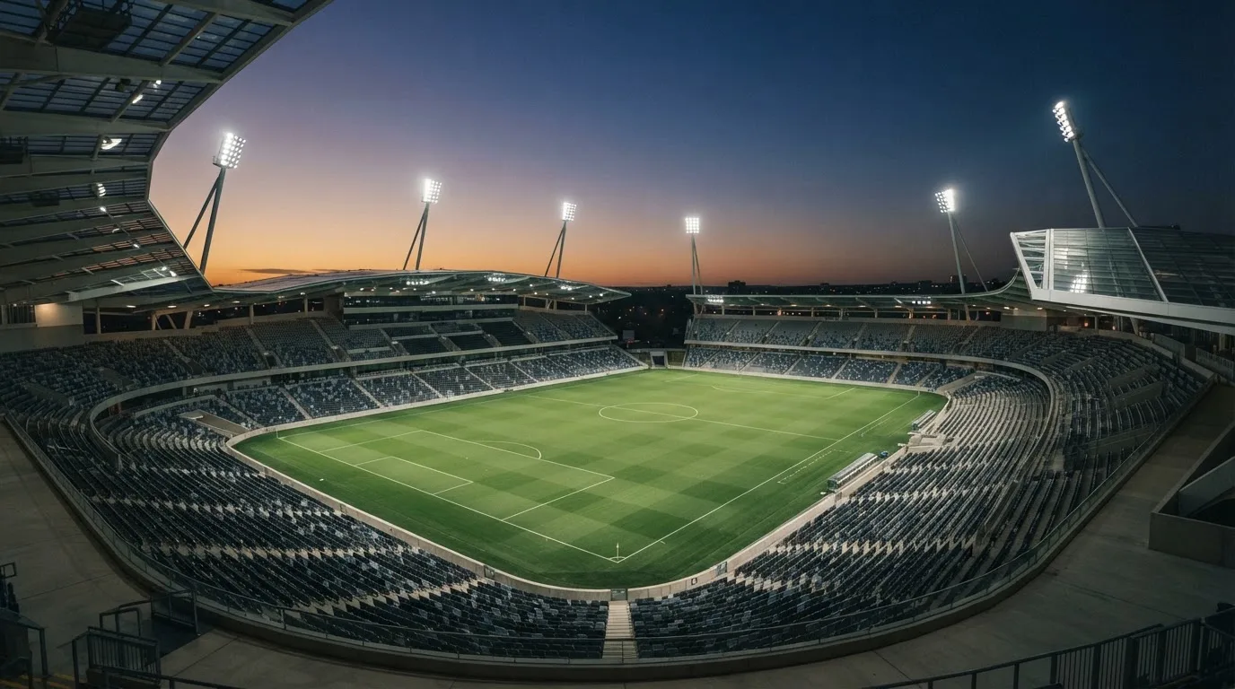 An empty football stadium with floodlight masts at dusk
