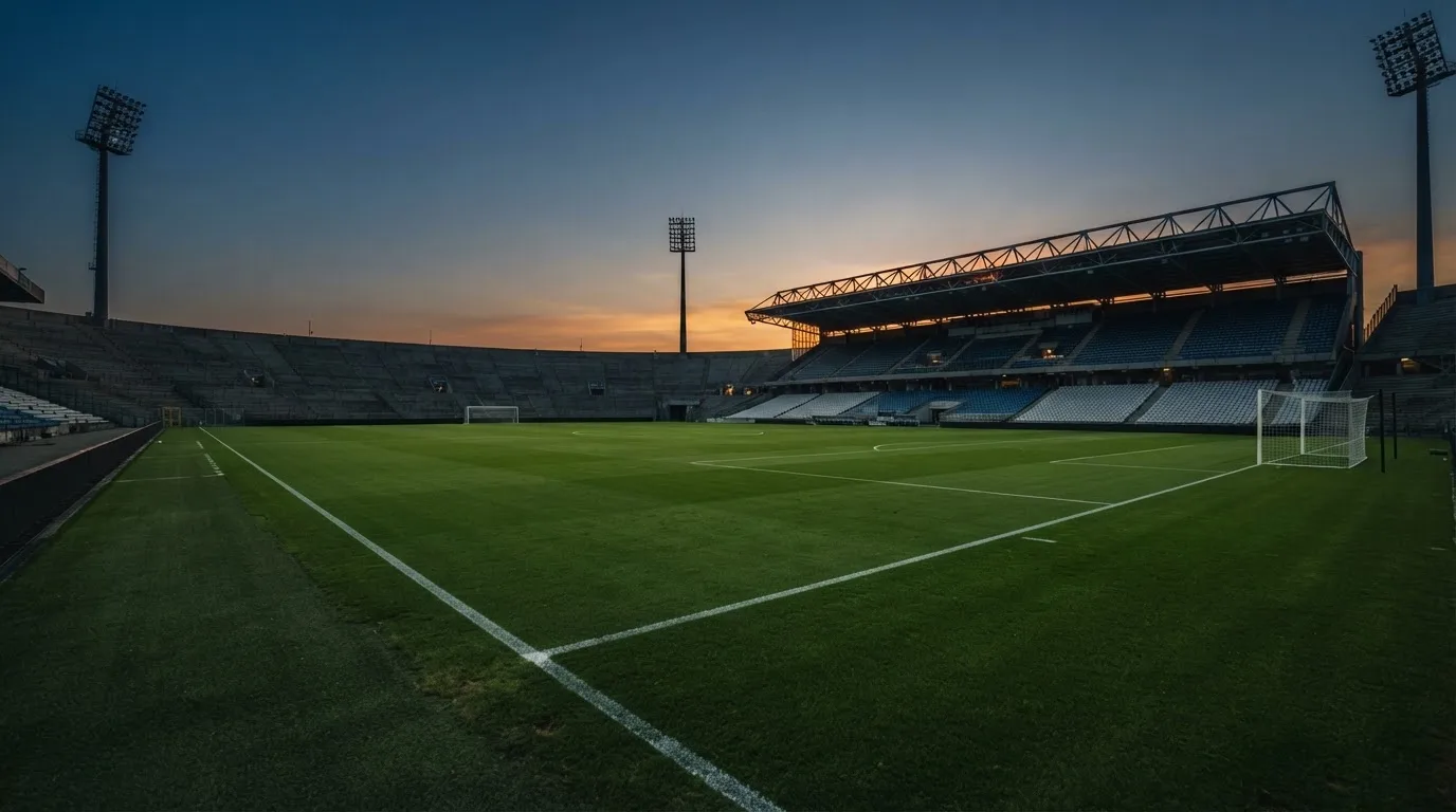 An empty football stadium with floodlight masts at dusk